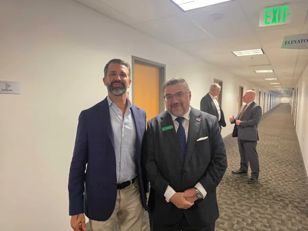 Two men posing for a photo in an office hallway